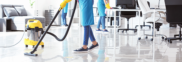 three cleaners in blue aprons working together to clean an office